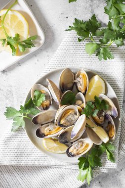 Açık gri bir masada seramik tabakta istiridye pişirdim. Deniz ürünleri tabağı. Yukarıdan görünüşü
