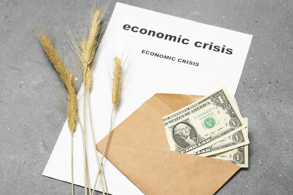 Economic crisis. Three dollars in an envelope, ears of corn, and a piece of paper with the words \