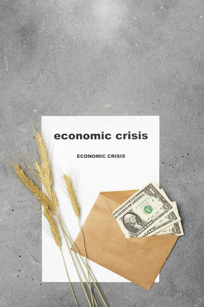 Economic crisis. Three dollars in an envelope, ears of corn, and a piece of paper with the words \