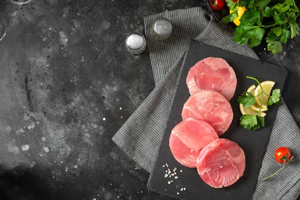Tuna medallions on a black slate on the black kitchen table. Healthy seafood