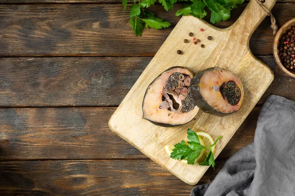 Wild sturgeon steak on a wooden Board on a brown wooden table. Healthy seafood. Top view with space for text