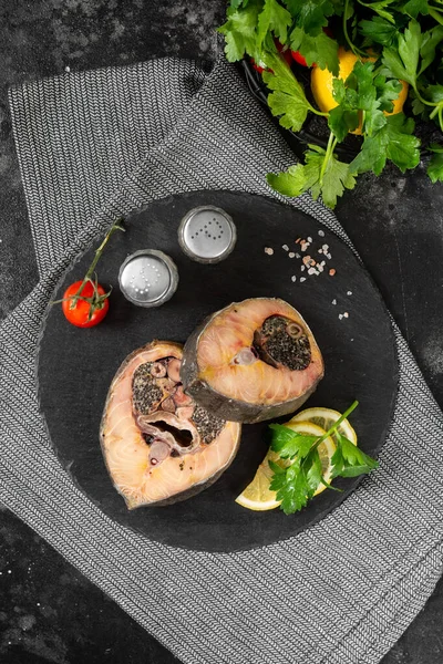 Wild sturgeon steak on a black slate Board on a black kitchen table. Healthy seafood. Top view with space for text