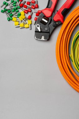 Elektrik kablolarını kıstırmak için bir araç. Gri arka planda elektrikçi veya inşaatçı için kripto aracı