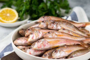 Açık gri mutfak masasında, beyaz bir seramik kasede, Karadeniz 'deki barabulka balığı. Bir sürü balık kırmızısı kefal. Karadeniz Barabulka