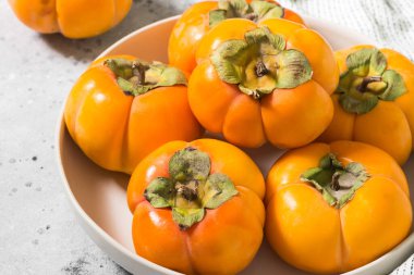 Açık gri arka planda beyaz bir kasede hurma. Hurma yakın çekim