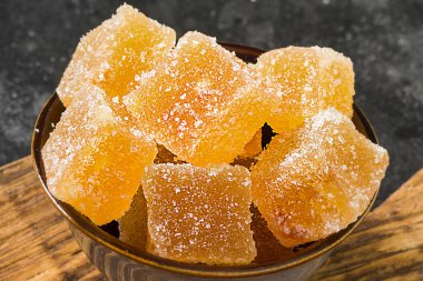 Siyah arka planda kahverengi bir kasede portakal reçeli. Marmelat dilimler.