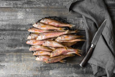 Karadeniz balığı, gri ahşap bir masada siyah bir kasede kırmızı kefal balığı. Bir sürü barabulka balığı. Metin için boşluk olan üst görünüm