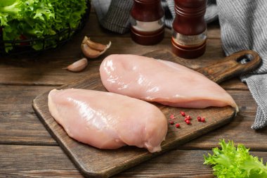 Tavuk göğsü fileto tahtanın üzerinde, kahverengi tahta bir masada. Çiğ tavuk göğsü.