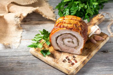 Gri ahşap bir masada, tahta bir tahtanın üzerinde sebzeli ve otlu rulo köfte. Pişmiş et. Metin için boşluk olan üst görünüm. Dikey oryantasyon. Kırsal biçim