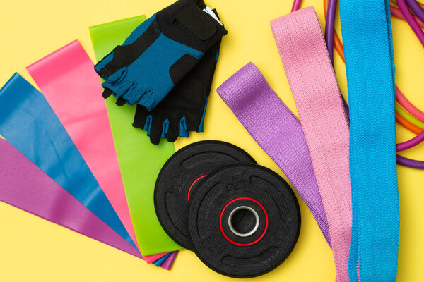 Расширители и эластичные ленты для фитнеса с разной степенью нагрузки на желтом фоне. Эластичные полосы для фитнеса. Спортивное оборудование для занятий спортом
