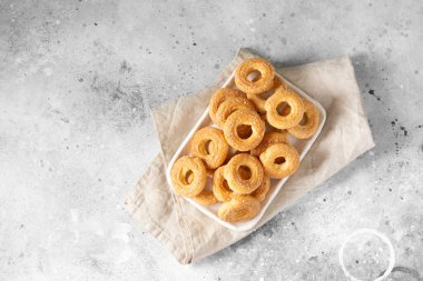Açık gri arka planda beyaz bir tabağa şeker serpiştirilmiş puf böreği. Kurabiyelere şeker serpilmiş. Tatlı hamur işleri. Metin için boşluk olan üst görünüm