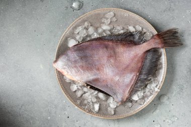 Kahverengi tabakta çiğ Dori balığı ve gri mutfak masasında buz. Yukarıdan görünüşü