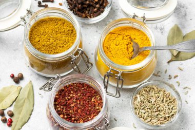 Açık gri bir masada cam kavanozlardaki baharatlar ve baharatlar. Metin için yeri olan baharatlar. Yukarıdan görünüşü