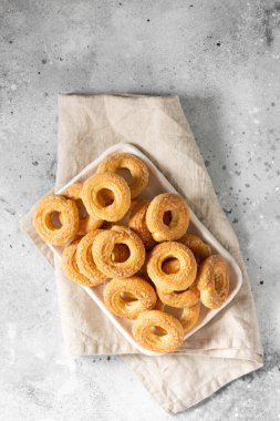 Açık gri arka planda beyaz bir tabağa şeker serpiştirilmiş poğaça. Kurabiyeleri şekerle serp. Tatlı hamur işleri. Metin için boşluk olan üst görünüm
