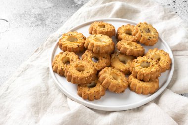 Açık gri mutfak masasında büyük beyaz seramik tabakta kurabiyeler. Tabakta bir sürü kurabiye var. Ev yapımı lezzetli hamur işleri.