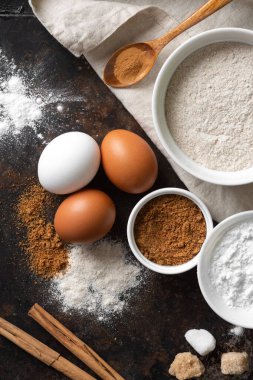 Mutfak zemininde pişirmek için gerekli malzemeler. Yumurta, un, tarçın, şeker, mutfak masasında soda. Pişirme hazırlığı kavramı. Yukarıdan görünüşü
