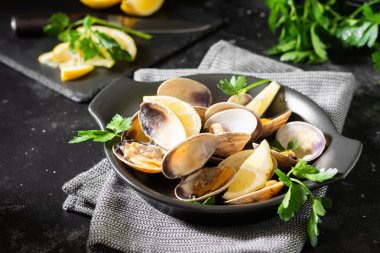 Siyah mutfak masasında siyah seramik tabakta istiridye pişirdim. Deniz ürünleri yemeği.