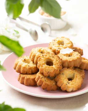 Işık masasında, pembe seramik tabakta, çörekler. Çiçek açan ağaçların arasındaki masada bir tabak kurabiye. Tabak kurabiyelerle dolu. Ev yapımı köylü kekleri. Pastalı çay partisi.