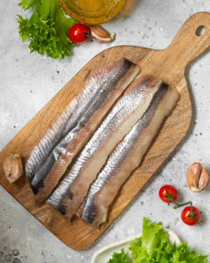  Açık gri mutfak masasında tahta bir tahtanın üzerinde fileto balığı. Mutfak masasında balık kesilmiş. Üst görünüm