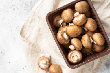 Açık gri mutfak masasında kahverengi tepside çiğ mantar. Mutfak arka planındaki tepside mantarlar. Metin için boşluk olan üst görünüm