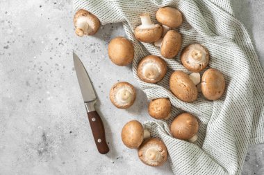 Çiğ mantarlar açık gri mutfak masasına yayıldı. Mutfak arka planında mantarlar. Metin için boşluk olan üst görünüm