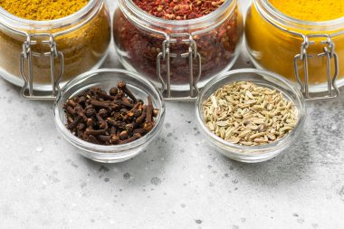 Açık gri bir masada cam kavanozlardaki baharatlar ve baharatlar. Metin için alanı olan baharatların yakın plan çekimi