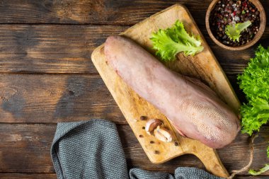 Kahverengi ahşap bir masada tahta bir tahtanın üzerinde sığır dili. Mutfak masasında çiğ sığır dili. Metin için boşluk olan üst görünüm