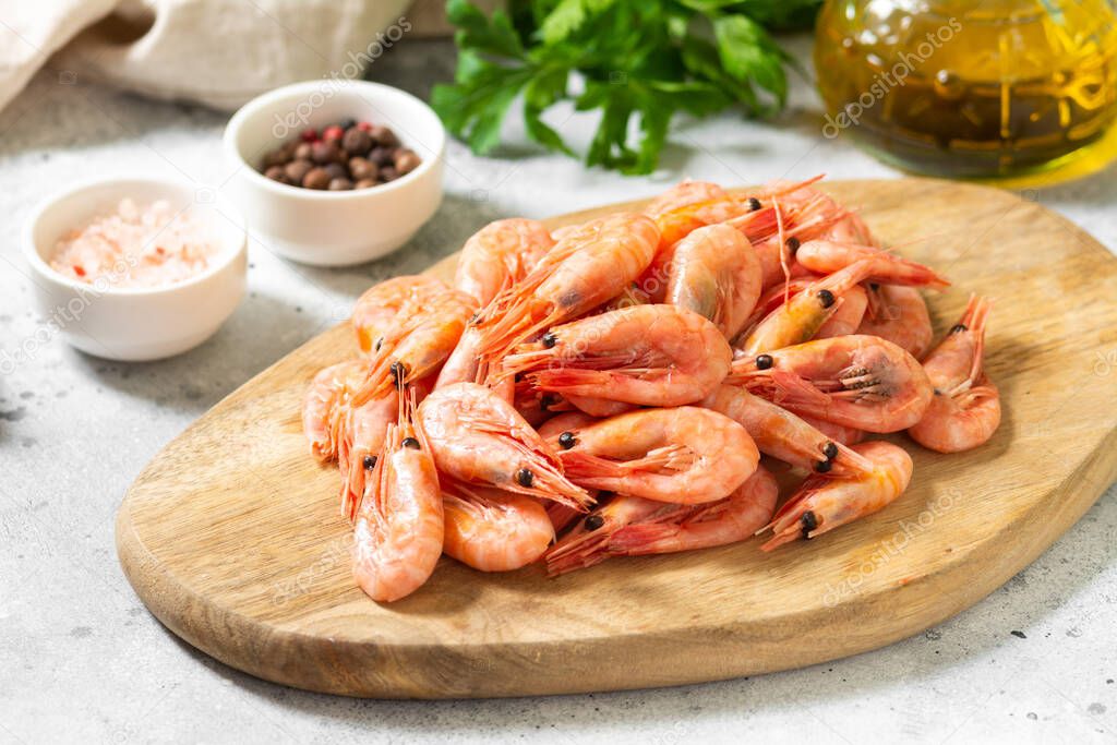 Prawns on a wooden Board on the light gray kitchen table. Lots of prawns on the serving Board