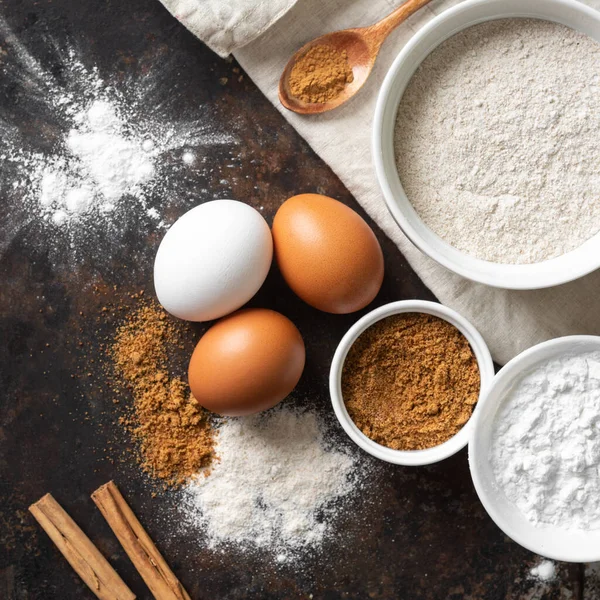 Mutfak zemininde pişirmek için gerekli malzemeler. Yumurta, un, tarçın, şeker, mutfak masasında soda. Pişirme hazırlığı kavramı. Yukarıdan görünüşü