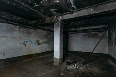 Dark and creepy dirty abandoned underground basement afrer fire. Walls in black soot