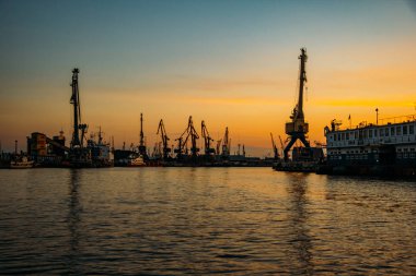 Günbatımı arka planında liman kargo vinçleri