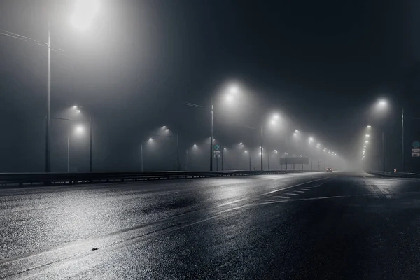 Foggy misty night road illuminated by street lights — Stock Photo, Image