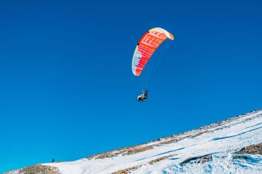 Flying on a paraglider above snowy mountains