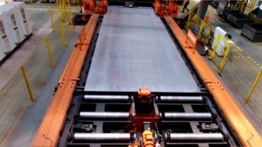 Metal işleme atölyesinde silindir konveyör üzerinde hareket eden çelik sac 