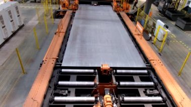 Metal işleme atölyesinde silindir konveyör üzerinde hareket eden çelik sac