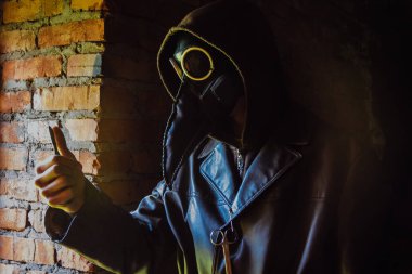 Kırmızı tuğlalı arka planda korkunç bir veba doktoru. Neşter ve makasla maskeli bir manyak. Cadılar Bayramı ve korku.