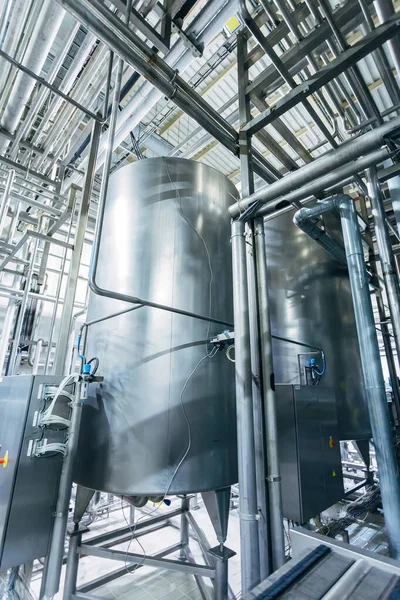 Industrial stainless steel fermentation vats in modern brewery.