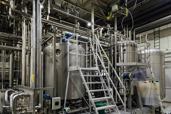 Modern brewing equipment in beer factory, steel vats for fermentation and maturation of beverage.