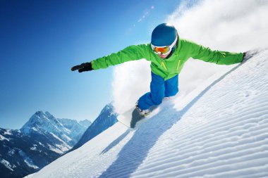 Snowboarder skiing in high mountains at beautiful sunny day. Clear weather and sky, prepared snow / piste.