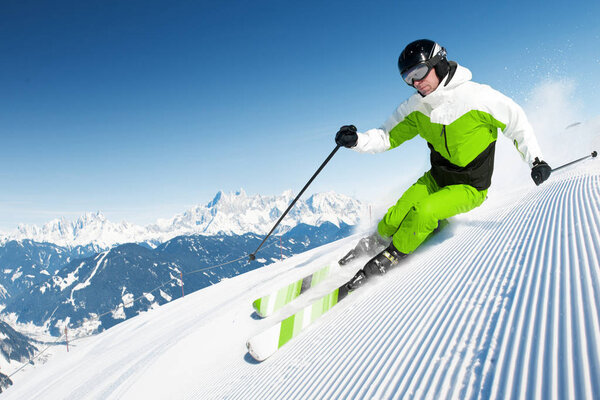 Skier in mountains, prepared piste and sunny day