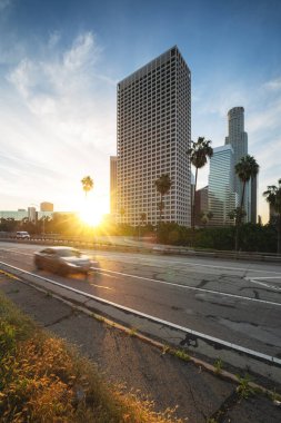 Los Angeles şehir merkezinde, otoyolu ve hareket halindeki arabası var. Los Angeles finans bölgesinde gün doğumu