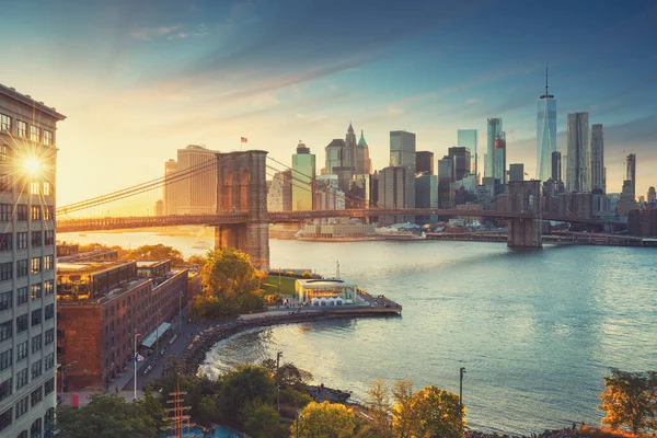 纽约市著名的布鲁克林大桥 以曼哈顿市中心金融区为背景 东河上的观光船和简旋转木马上美丽的落日 — 图库照片