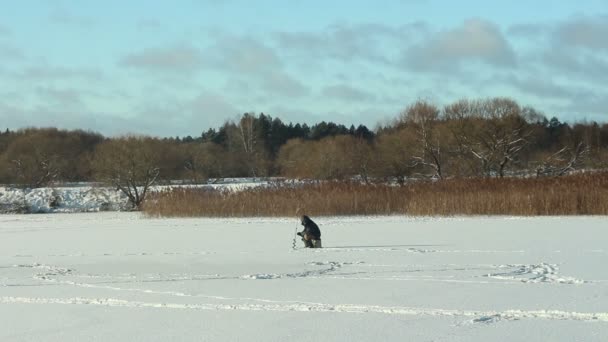 Pescatore seduto sul fiume coperto di ghiaccio — Video Stock