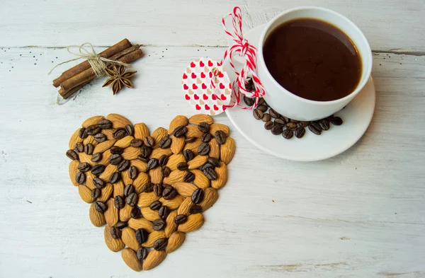 Чашка кофе и сердце с миндалем на белом фоне — стоковое фото