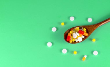 Hap, tablet, vitamin, ilaç, omega 3 balık yağı, jel kapsülleri, ilaç ve sağlık hizmetleri için gıda takviyesi dolu tahta kaşık. yeşil arkaplan.