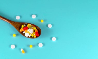 Hap, tablet, vitamin, ilaç, omega 3 balık yağı, jel kapsülleri, ilaç ve sağlık hizmetleri için gıda takviyesi dolu tahta kaşık. Mavi arkaplan.