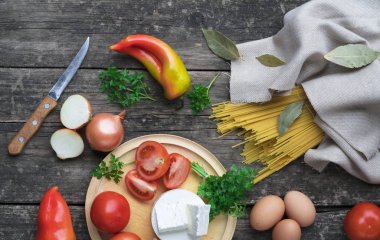 Makarna ve makarna sosu yapmak için malzemeler. Fesleğen, soğan, bıldırcın yumurtası, domates, badem, koyu arkaplanda parmesan peyniri.