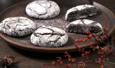 Çatlaklı çikolatalı kurabiyeler, üzerine şeker serpiştirilmiş. Ev yapımı pişirme, ahşap arka plan