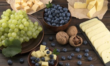 Tahta bir arka planda peynir, yabanmersini ve üzüm