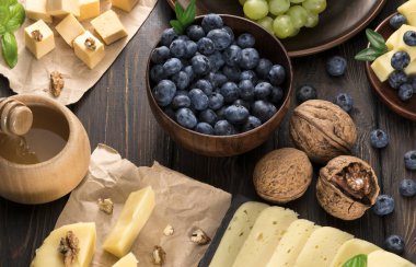 Tahta bir arka planda peynir üzümü ve yaban mersini.